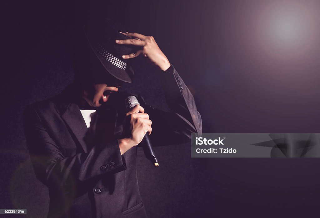 Main de Songer tenant le micro et chantant sur le dos noir - Photo de Karaoké libre de droits