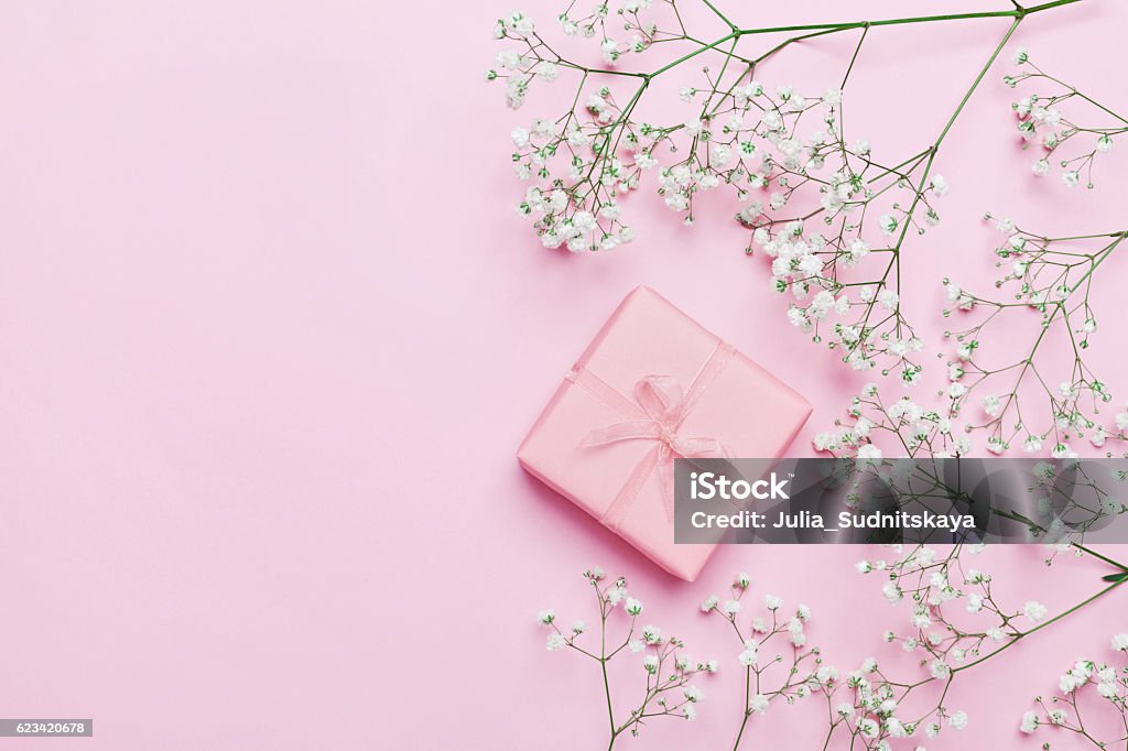 Gift or present with flowers on pink table. Flat lay. Gift or present box and flower on pink table from above. Pastel color. Greeting card. Flat lay style. Gift Stock Photo