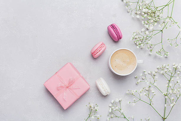Cup of coffee, macarons, gift or present, flowers. Flat lay. Morning cup of coffee, cake macaron, gift or present box and flower on light table from above. Beautiful breakfast. Flat lay style. cake models stock pictures, royalty-free photos & images