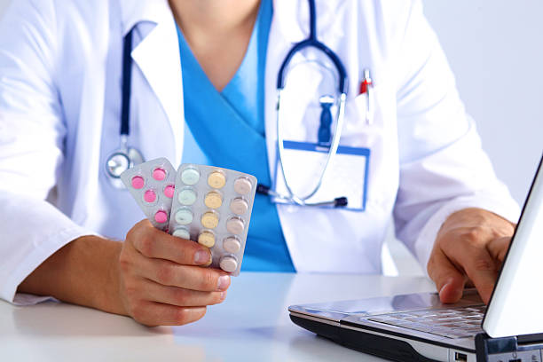 istock the doctor writes a prescription pill on the computer 623423650