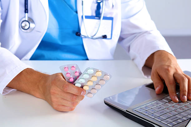 istock the doctor writes a prescription pill on the computer 623423716