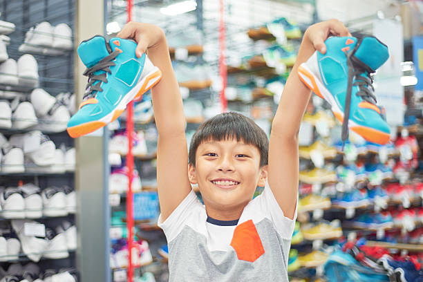 boy holding chosen shoes smiling in store stock photo