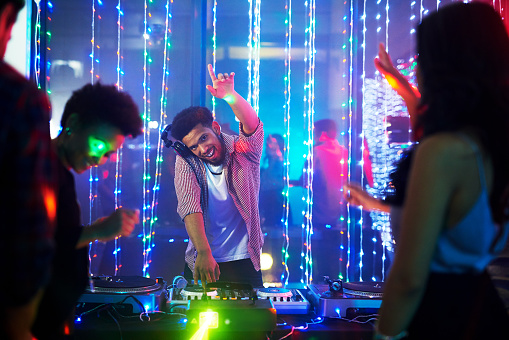 Portrait of a happy young DJ playing music at a party in a nightclub