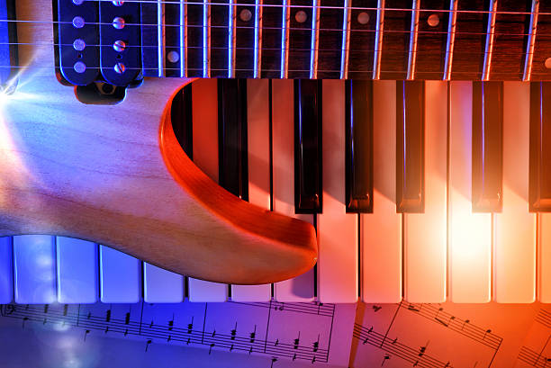 Electric guitar and synthesizer on sheet music with red and blue lights. Horizontal composition. Top view
