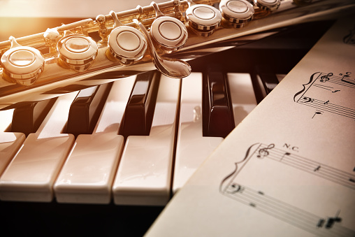 Piano y flauta con brillo dorado y partitura frontal photo