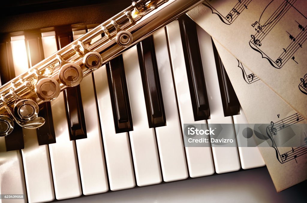Piano and flute with golden shine and sheet music top Piano and flute with golden shine and sheet music. Horizontal Composition.Top view Musical Instrument Stock Photo