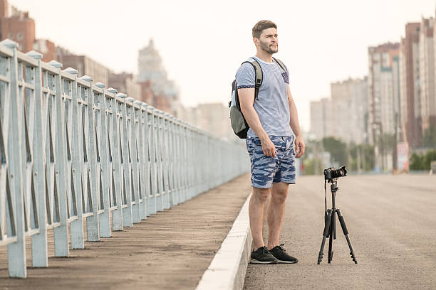 man with camera on tripod - reportage photographer photographing street imagens e fotografias de stock
