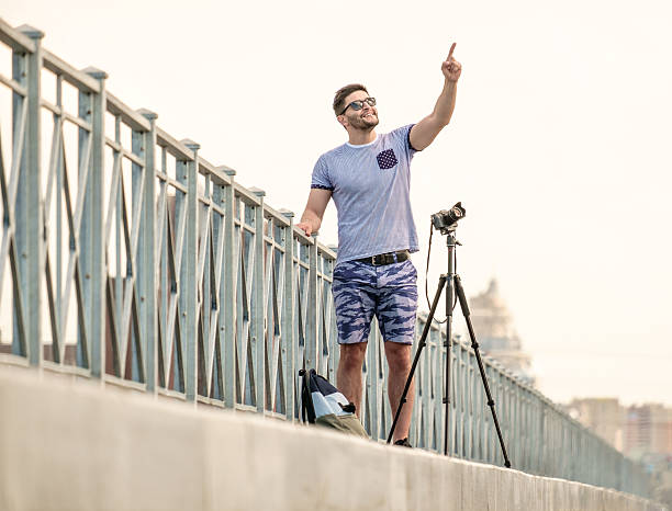 man with camera on tripod - reportage photographer photographing street imagens e fotografias de stock