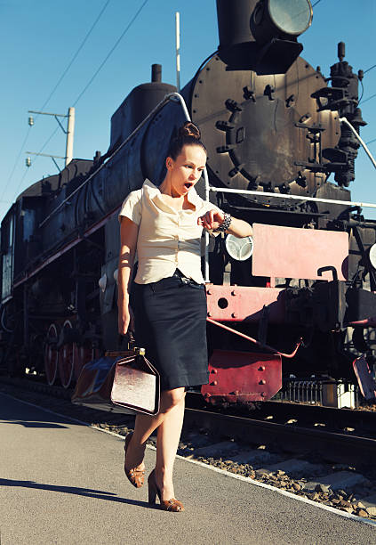 istock Woman with a suitcase looks at her clock 623441340