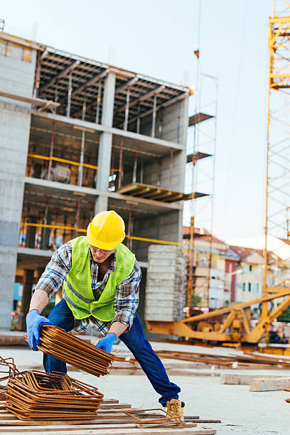 istock Construction worker picking up steel rods for armature 623442028
