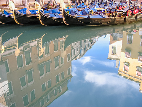 Venice historic gondolas boats reflected on water of the town canals.
