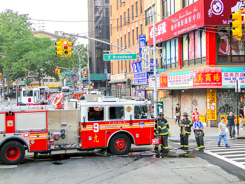 New York, USA, June 2 2011:  a red FDNY truck is parked on a crossroad while firefighters working in Chinatown, East Manhattan.