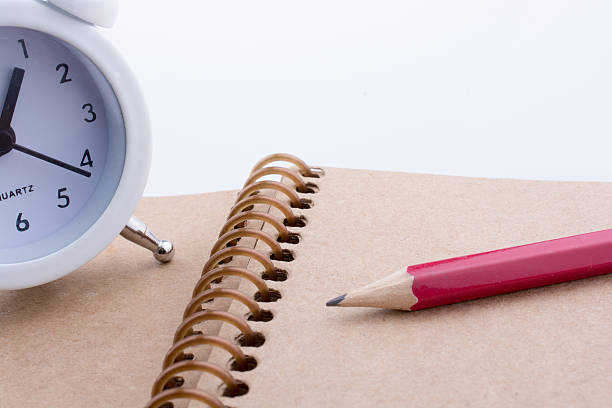 istock Color pencil and an alarm clock placed on a notebook 623451690