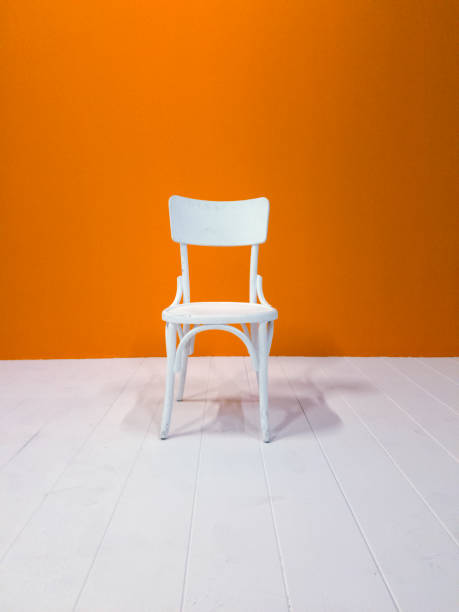 istock White wooden chair and orange painted wall 623455818