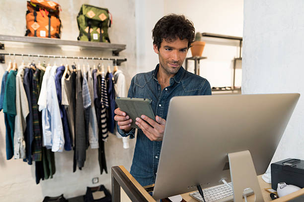 мужчина владелец fashion store с цифровым планшетом и компьютером - clothing store clothing shopping fashion стоковые фото и изображения