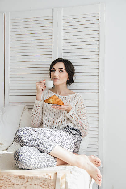 istock Girl drinking coffee and a croissant in bed 623475688