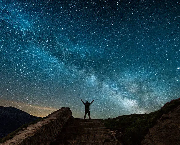 The milky way and the silhouette of a man with arms raised
