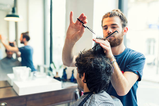 man gets a haircut at his barber - saç kesmek stok fotoğraflar ve resimler