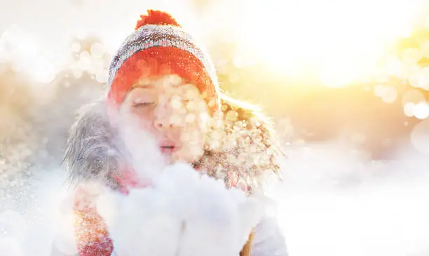 happy woman is happy and blowing snow in the winter nature