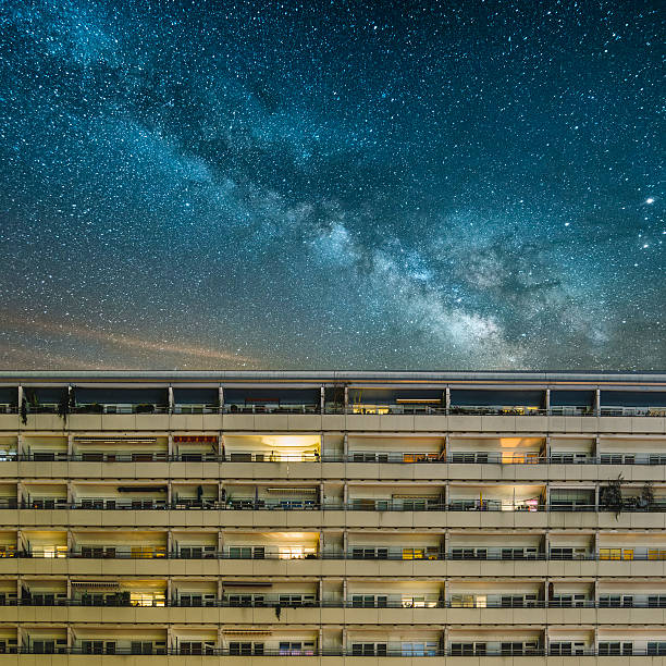 Residential building under a starry sky A communist-styled residential building at night in East Berlin, Germany, with lights coming from some of the windows and the mily way in the sky. east germany photos stock pictures, royalty-free photos & images