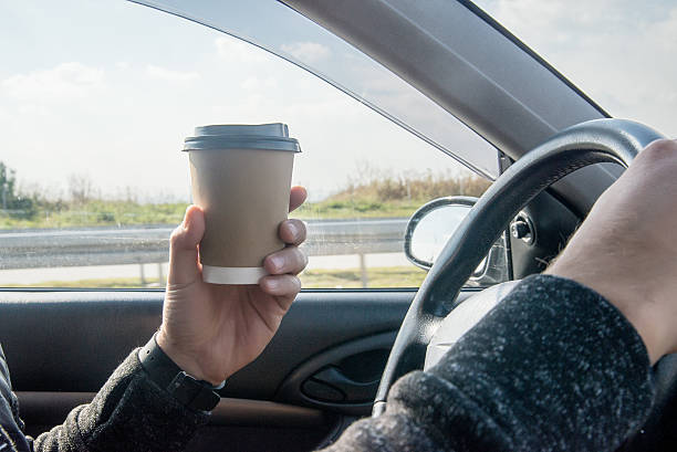 istock man drinking coffee and holding a  wheel while driving  car 623486524