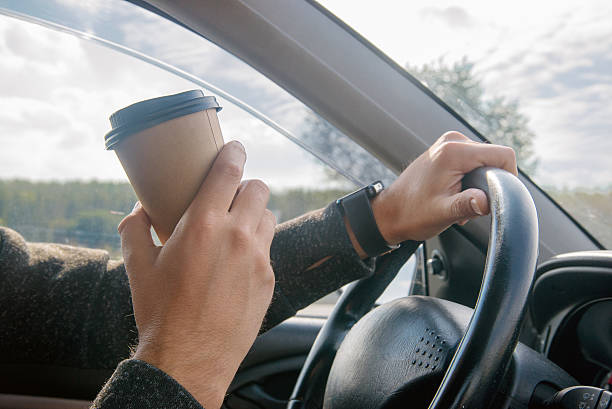 istock man drinking coffee and sitting at the wheel while driving 623486622