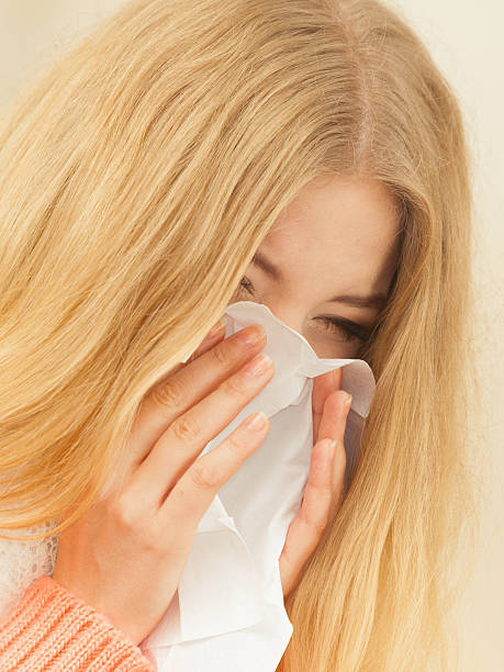 istock Sick ill woman in autumn park sneezing in tissue. 623489028