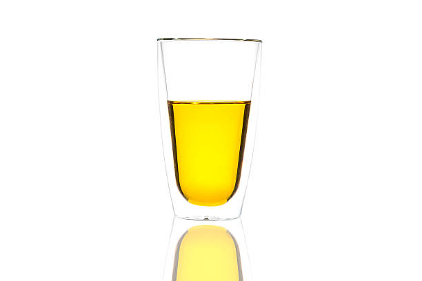 istock Yellow water in glass with reflection on white background 623489900
