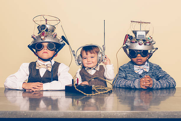 Three Boys Dressed as Nerds with Mind Reading Helmets A young boy imagines reading minds of his two friends with a homemade science project. They are dressed in casual clothing, glasses and bow ties. They are serious and sitting at a table with helmets on their heads in front of a beige background. Retro styling. nerd kid stock pictures, royalty-free photos & images