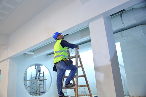 Plaster applying plaster on a new drywall installation.