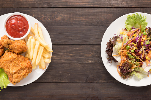 Fresh salad and Fried chicken and french fries on the wooden background. contrasting food.