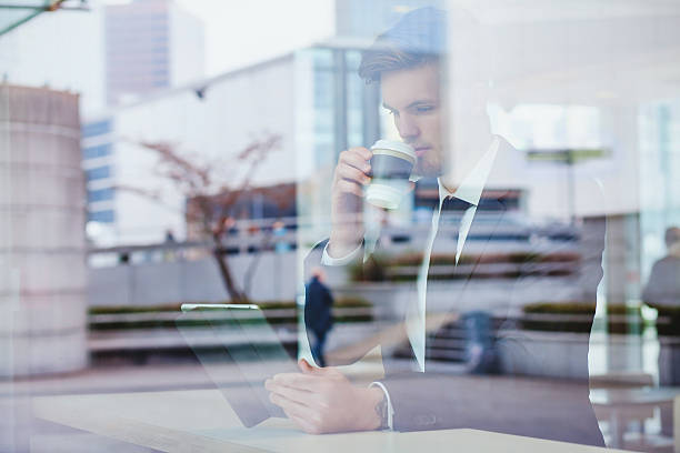 businessman reading news online businessman reading news online and drinking coffee in airport cafe newspaper airport reading business person stock pictures, royalty-free photos & images