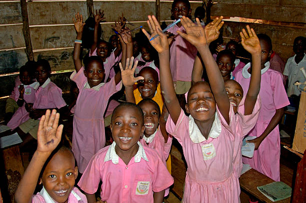 Children in pink school uniform in their school waving. stock photo