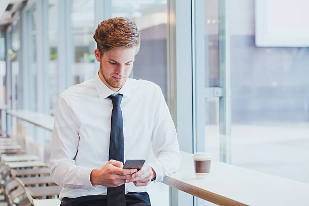 businessman using smartphone businessman reading news and emails on his smartphone newspaper airport reading business person stock pictures, royalty-free photos & images