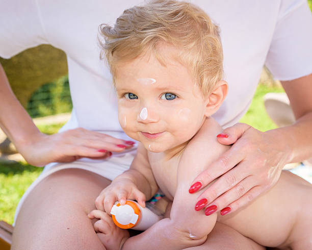 Infant with cream on his face Child with cream on his face lying on Mother's legs after a bath. creaming stock pictures, royalty-free photos & images