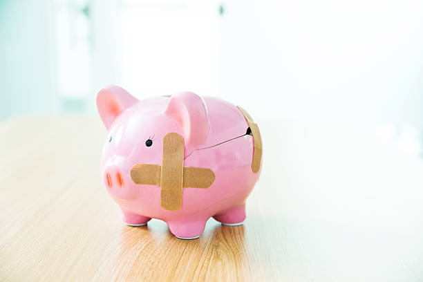 バンドエイド付きの壊れた貯金箱 - piggy bank healthcare and medicine wound currency ストックフォトと画像