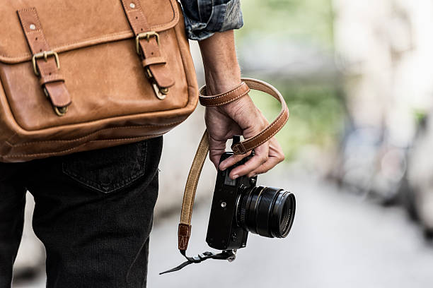 photographer with leather bag in the city - fotograaf stockfoto's en -beelden