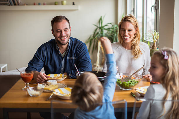 Family lunch at home Happy family enjoying lunch while kids playing. kids eating noodles stock pictures, royalty-free photos & images