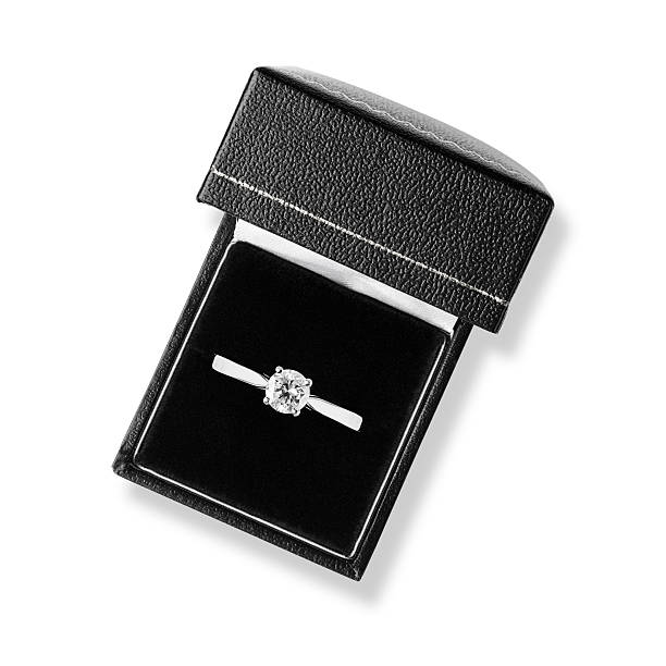 Single diamond solitaire engagement ring in black leather box A sparkling solitaire diamond ring is in black leather ring box on a velvet cushion. The 1-carat diamond is set on a platinum band. The ring box is on a white background with a clipping path. Shot from overhead, looking down into the box. jewelry box photos stock pictures, royalty-free photos & images