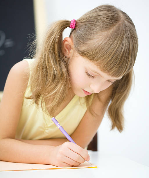istock Little girl is writing using a pen 623523630