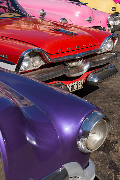 Vintage collector car amber-colored headlight in a chrome frame, close up, positioned upper left in a vertical composition, with the backdrop formed by the green and orange vehicle bodywork.