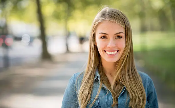 Portrait of a young woman at the park looking very happy and smiling - lifestyle concepts