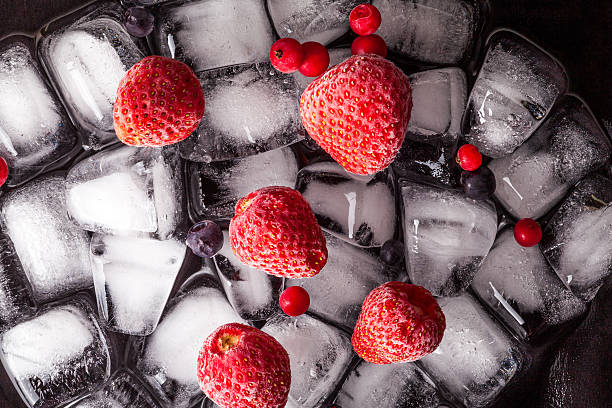 istock Frozen strawberries and cranberries lying on ice cube. Dark background 623528688