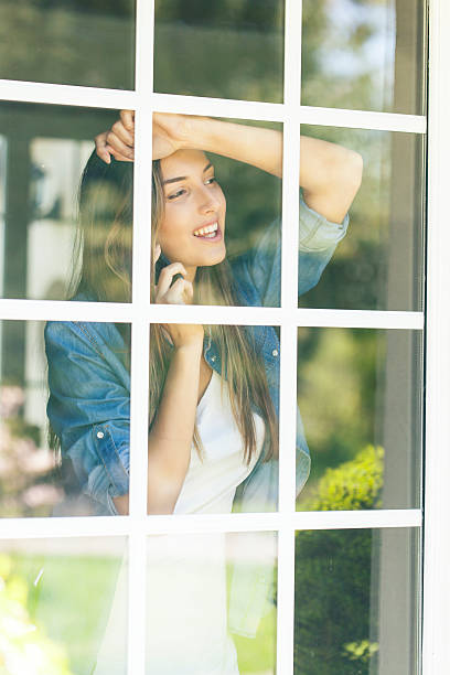 istock Woman leaning on window and talking on phone 623530868