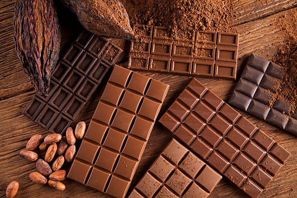 barre chocolatée, bonbons sucrés, fèves de cacao et poudre sur bois - chocolat photos et images de collection