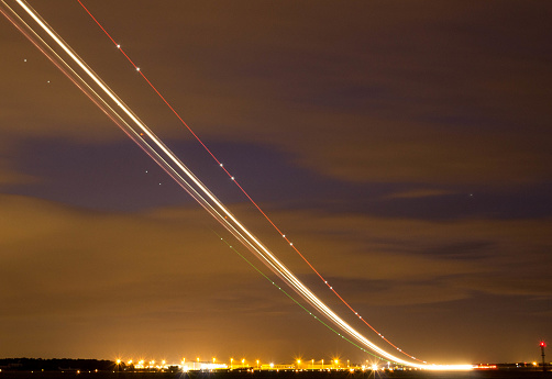 An unknown airline lands at night.  The light trails from the long shutter speed.