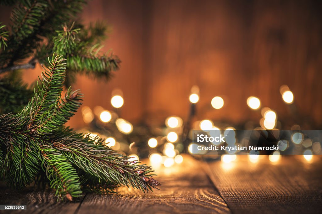 Spruce Tree branch on Wood Background Spruce Tree branch on Wood Background and defocused lights. Christmas Lights Stock Photo