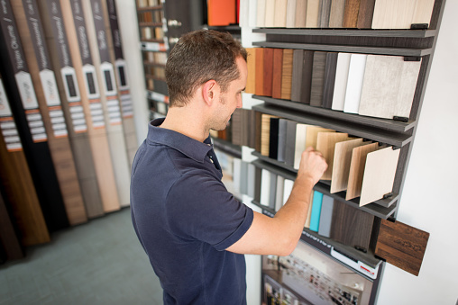 Man at a floor store looking at wood samples - home improvement concepts