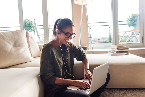 heureuse jeune femme utilisant son ordinateur portable à la maison - document reading human hand caucasian photos et images de collection