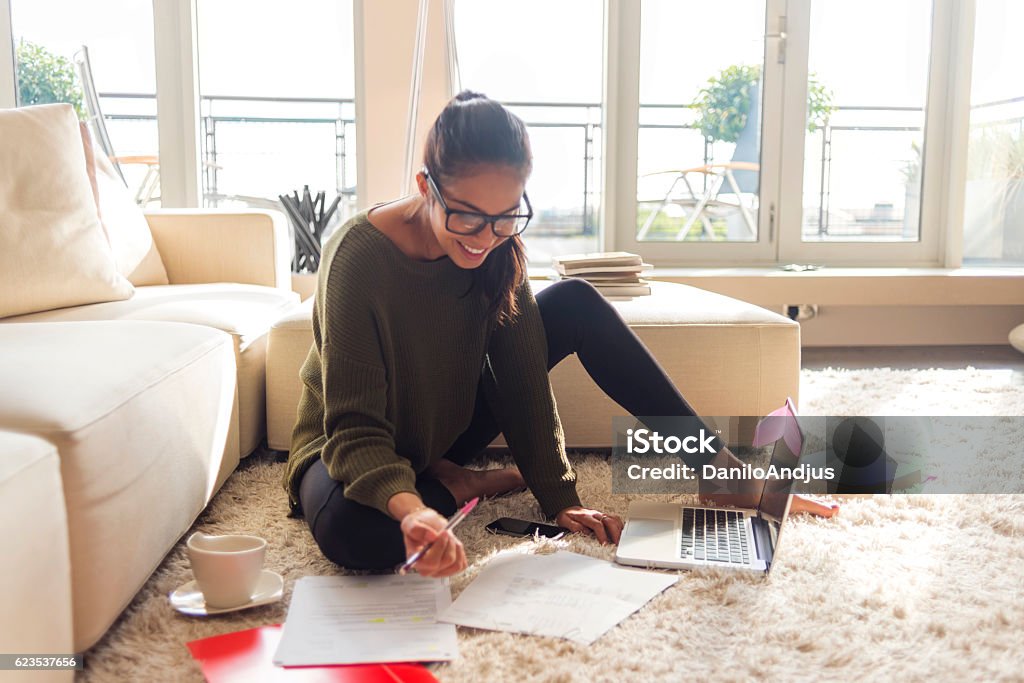 smiling young woman studying in her living room Happiness Stock Photo
